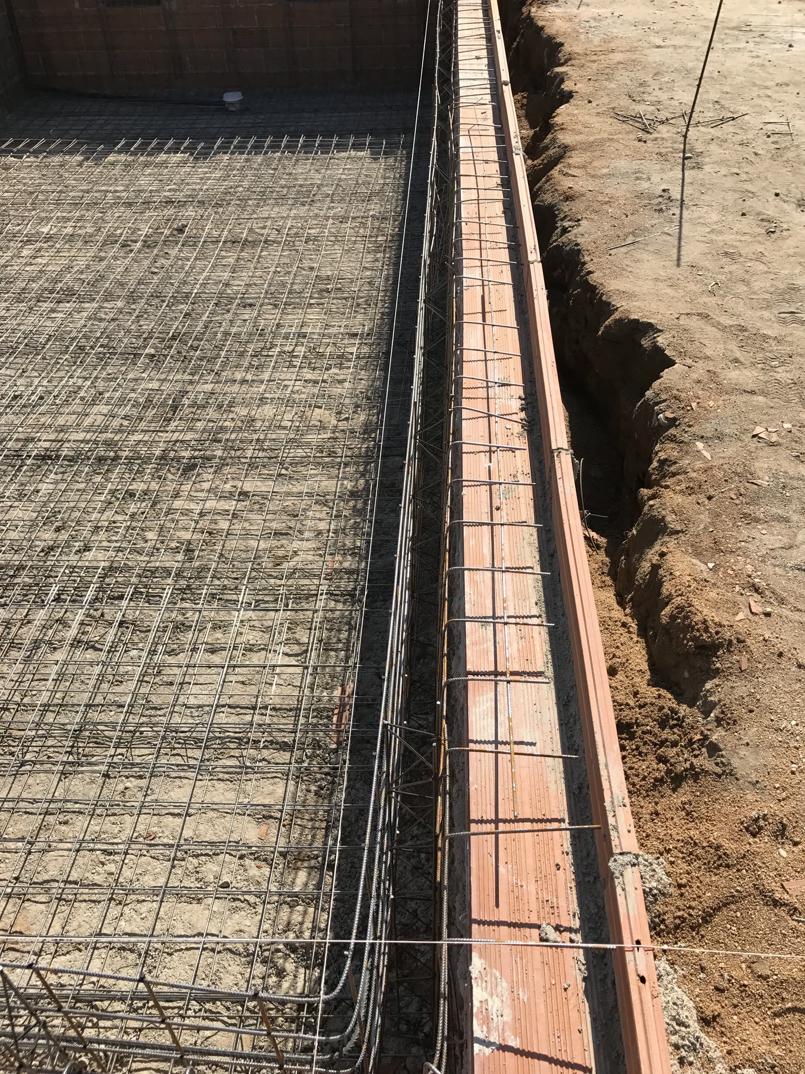 Armadura montada en la zanja contra el terreno excavado, con el encofrado colocado solo en la cara vista y la otra cara apoyada directamente en la tierra.
