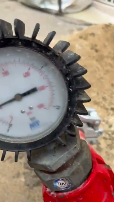 Manómetro de presión de la bomba, sucio de hormigón, en obra.