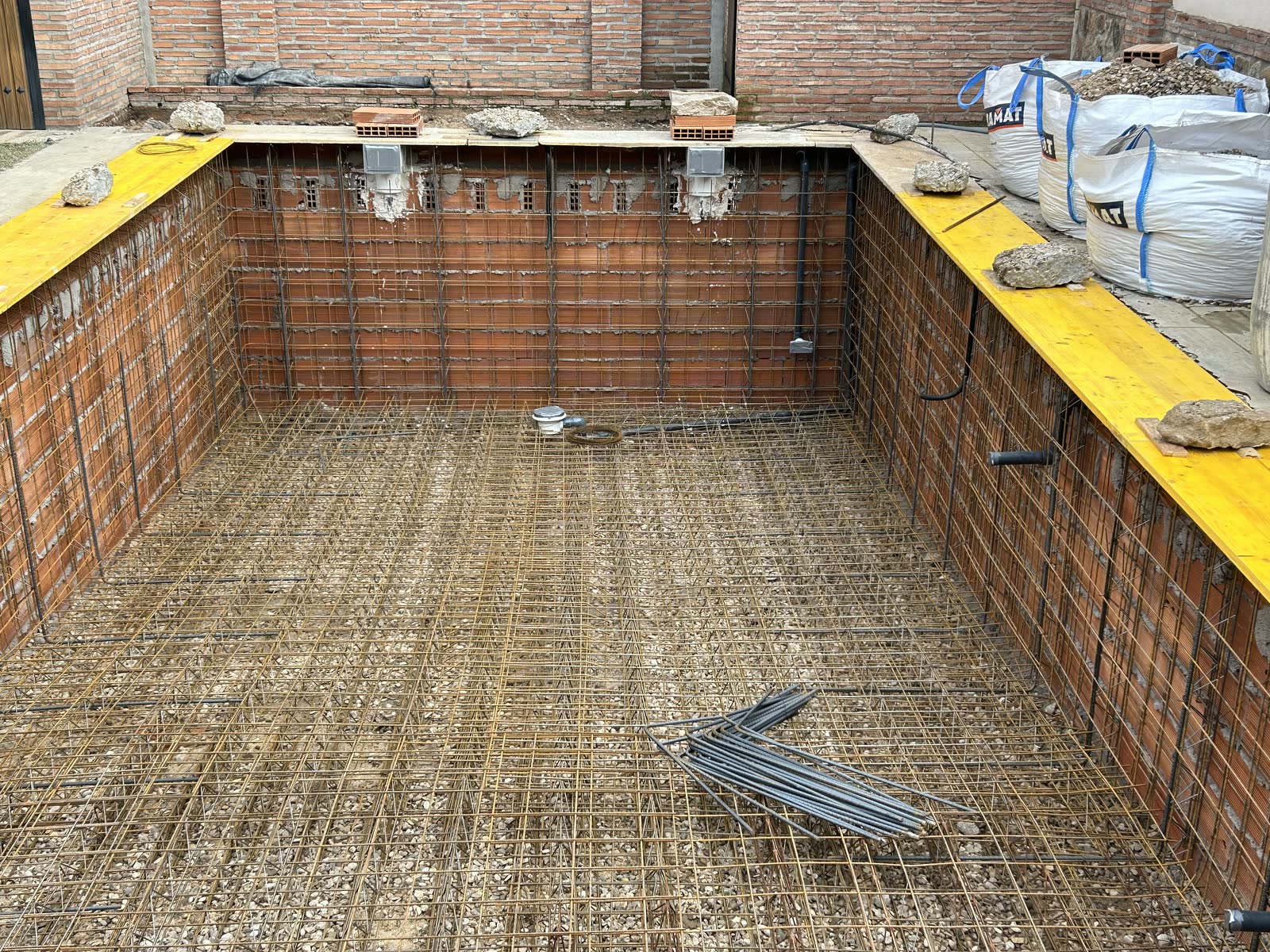 Vaso de piscina armado con doble mallazo, con la instalación hidráulica ya embebida y el encofrado de coronación colocado, el día antes de proyectar el hormigón.
