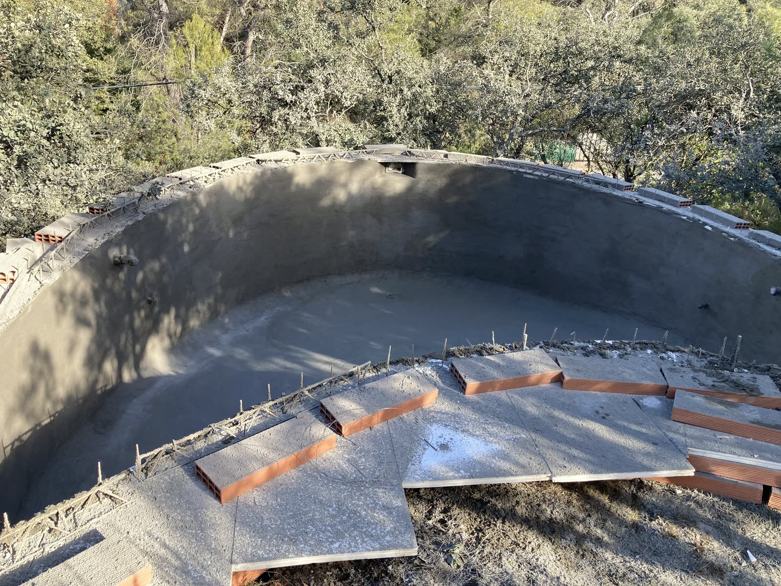 Vaso de piscina de planta curva ya gunitado, con la escalera formada en el propio hormigón y la pared describiendo un arco continuo.