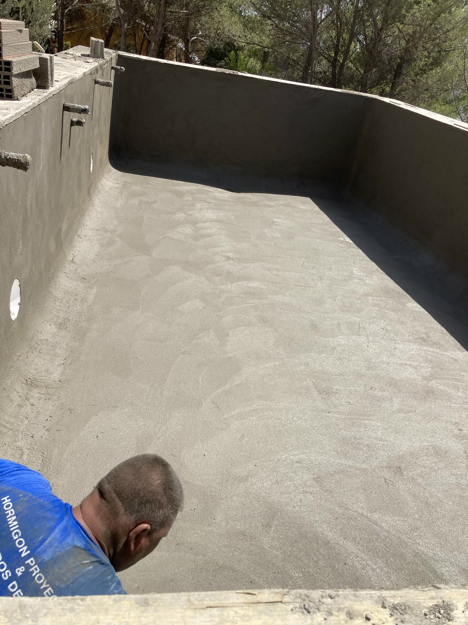Vaso de piscina recién gunitado, con la superficie continua y sin coqueras, durante el repaso final antes del curado.