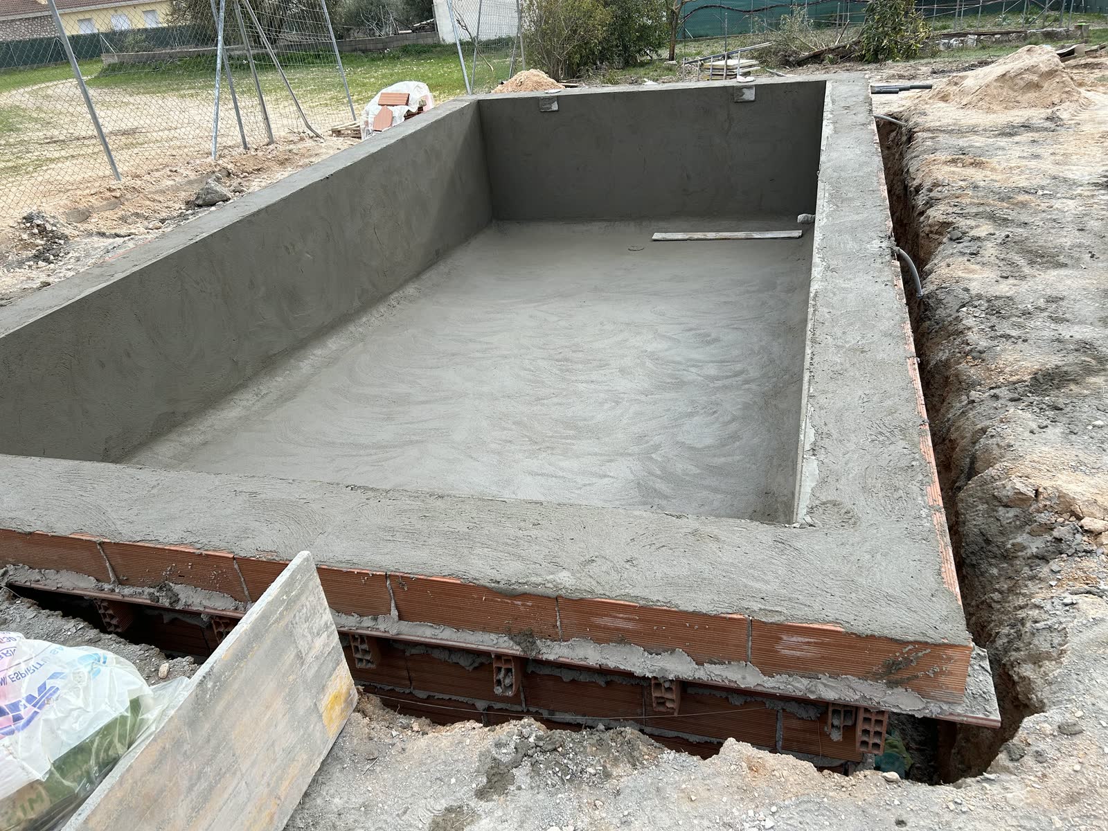 Vaso de hormigón terminado dentro de la zanja, ejecutado contra el muro de fábrica que ya estaba y sin haberlo desmontado.